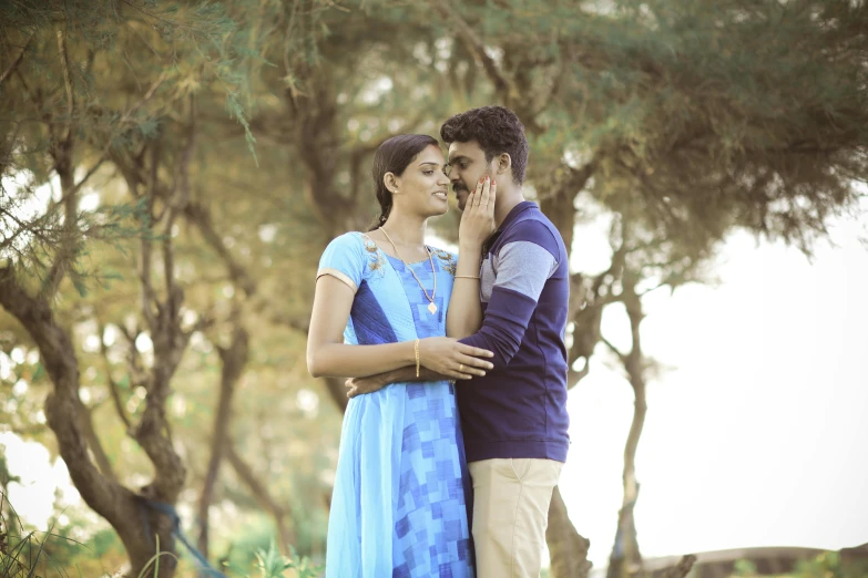 a man and woman cuddle underneath trees