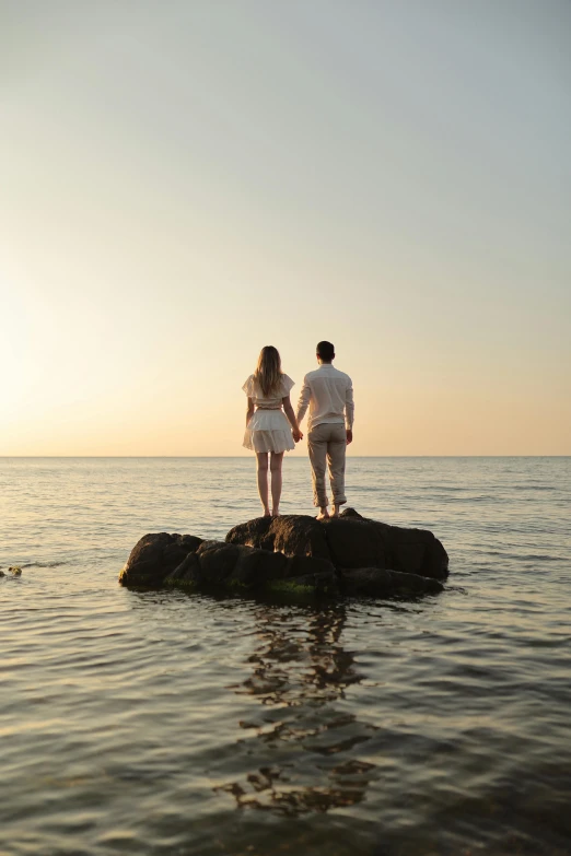 a couple is standing on top of a rock