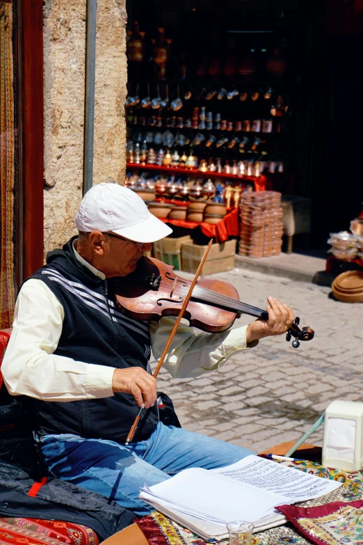 a man sitting on the ground playing a violin