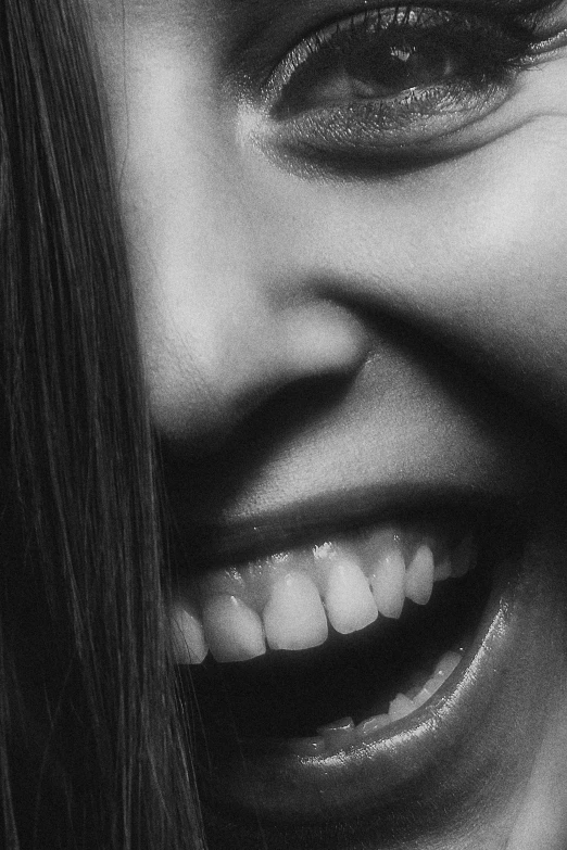 a black and white po of a woman smiling with her teeth slightly open