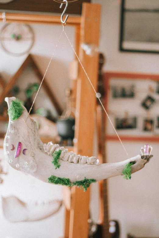 a white bed hanging from the ceiling with green and white decorations