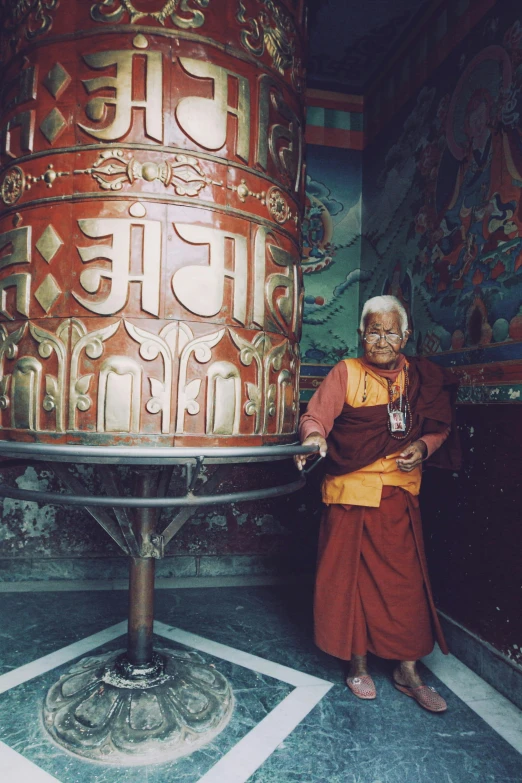 the man in a monk's outfit is standing by a large pillar