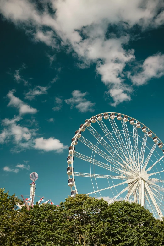 a ferris wheel is shown in a green field with clouds