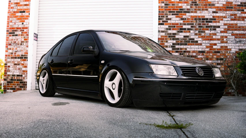 the black vw golf is parked in front of a red brick building