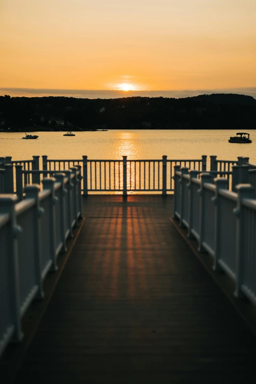 the boardwalk is wide as sun rises over a body of water