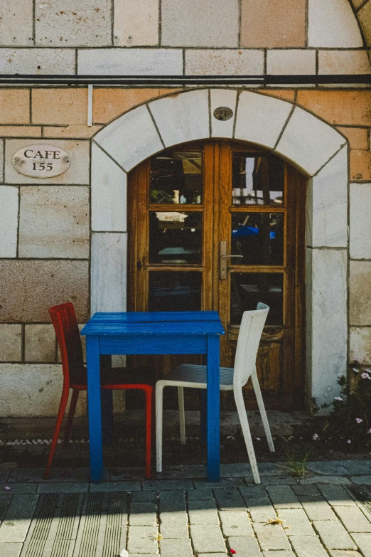 there are two tables and chairs outside a cafe