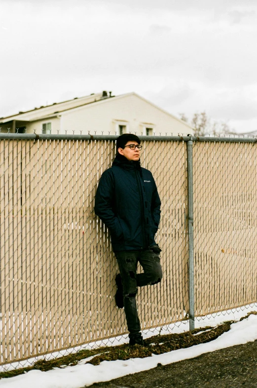 a man leaning against a fence while standing in front of it