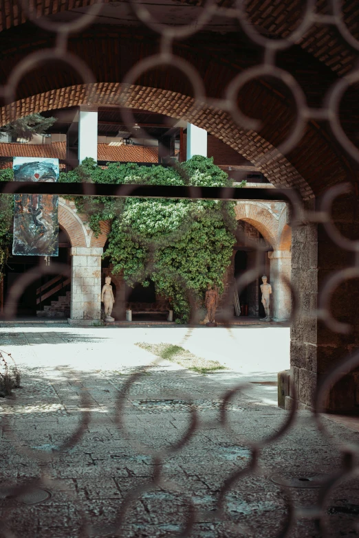 an arch with a courtyard behind it with some people walking through it
