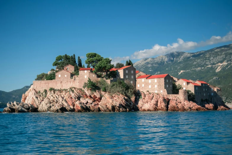 there is a building on a small rock outcropping in the middle of the ocean