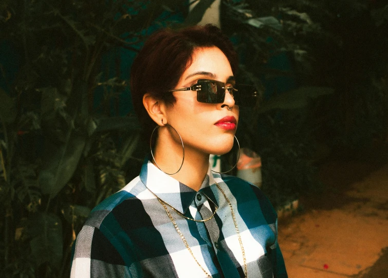 a woman with red lipstick in sunglasses, plaid shirt, and black neck tie