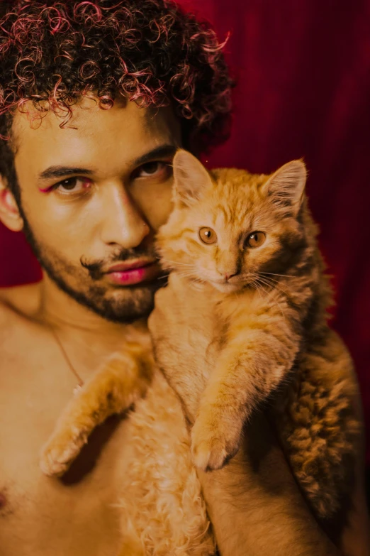 the man has curly hair and holds a cat