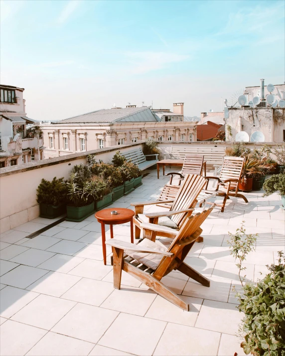 several wooden chairs on top of a roof with potted plants