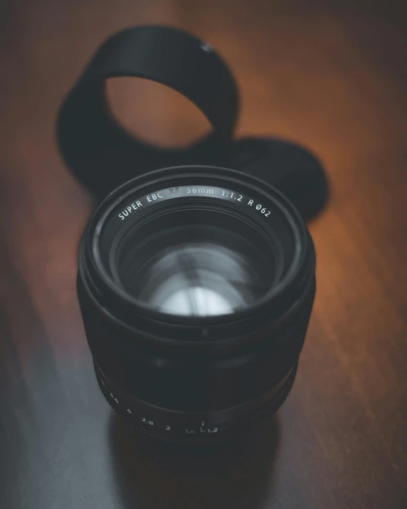 a camera lens on a wooden table with the lens hood up