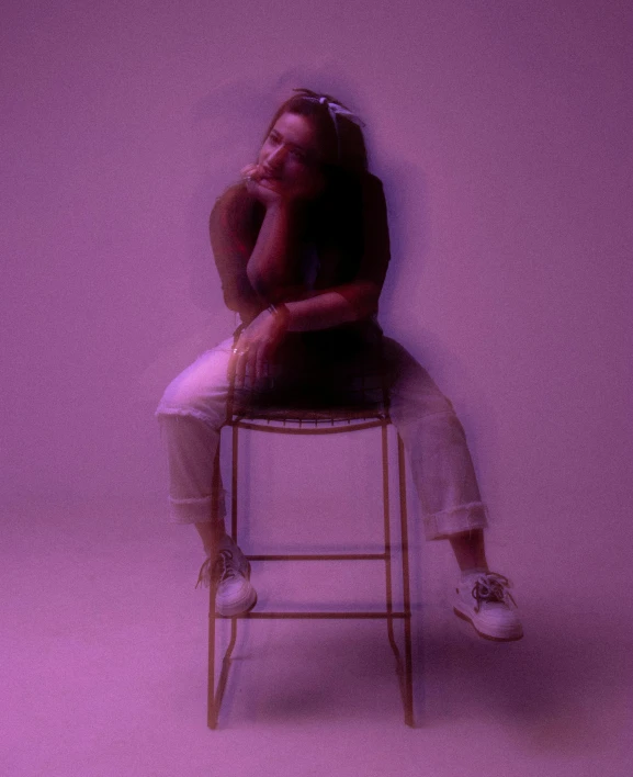 woman sitting on stool with arms crossed behind head