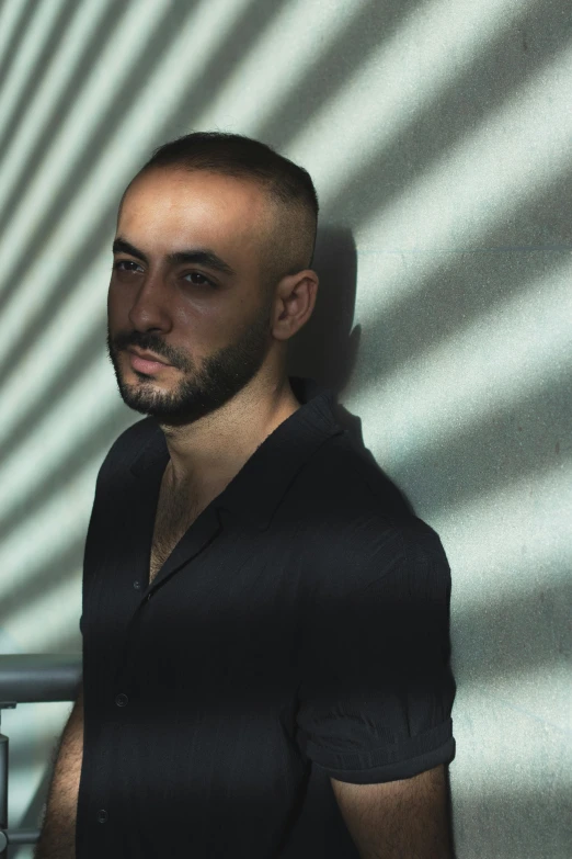 a man with a beard standing in front of a wall