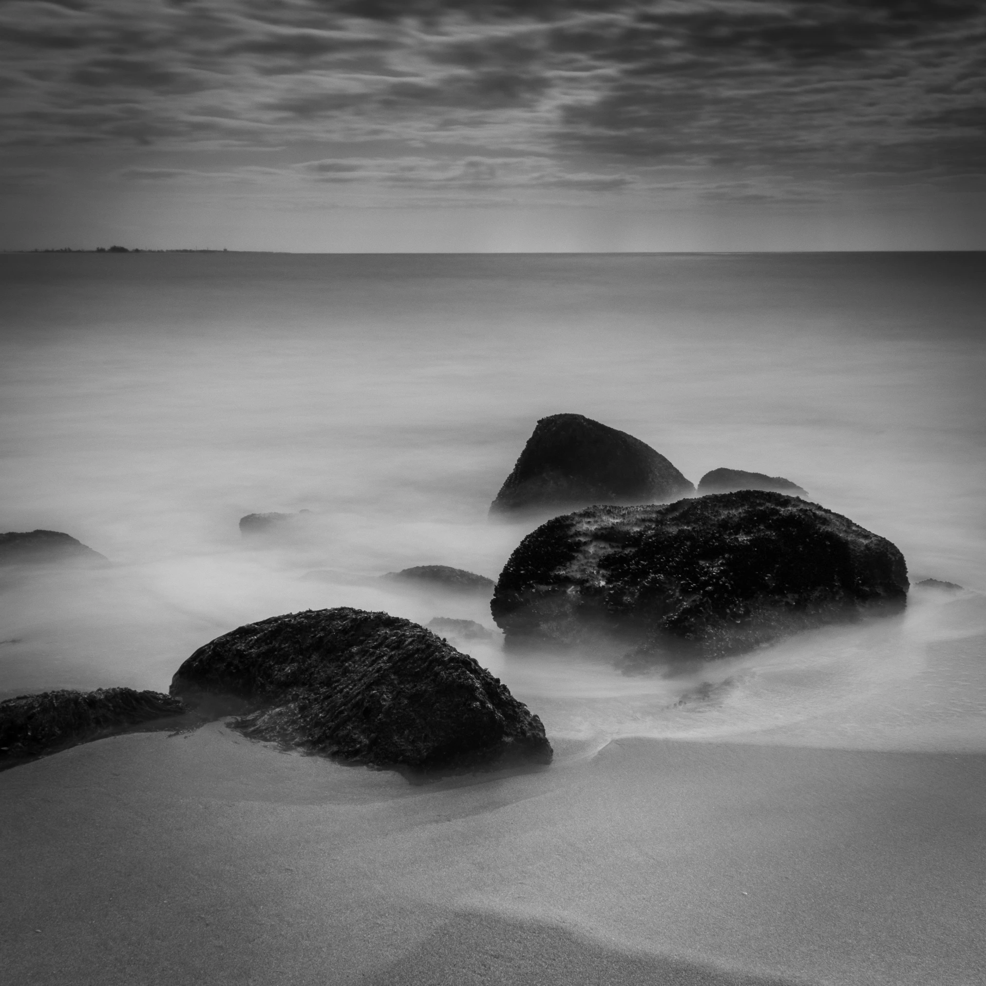 some rocks in the sand water and sky