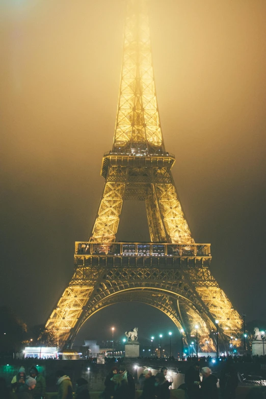 people are sitting outside of the eiffel tower in the fog