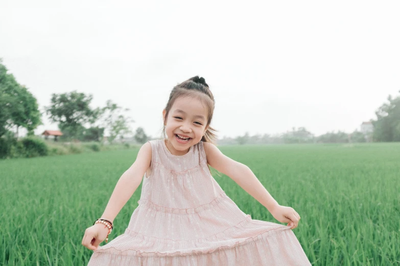 a girl in a pink dress stands on one arm and smiles into the camera