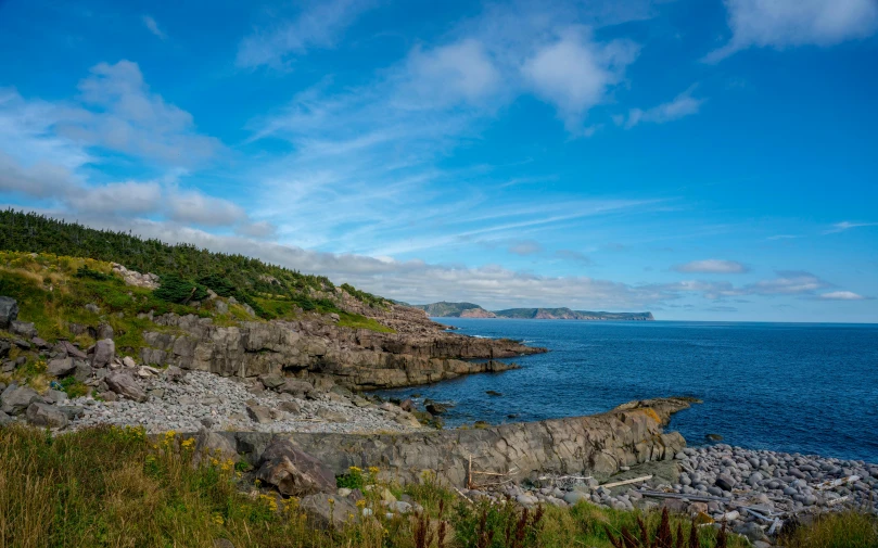 a rocky hillside beside the ocean on a sunny day