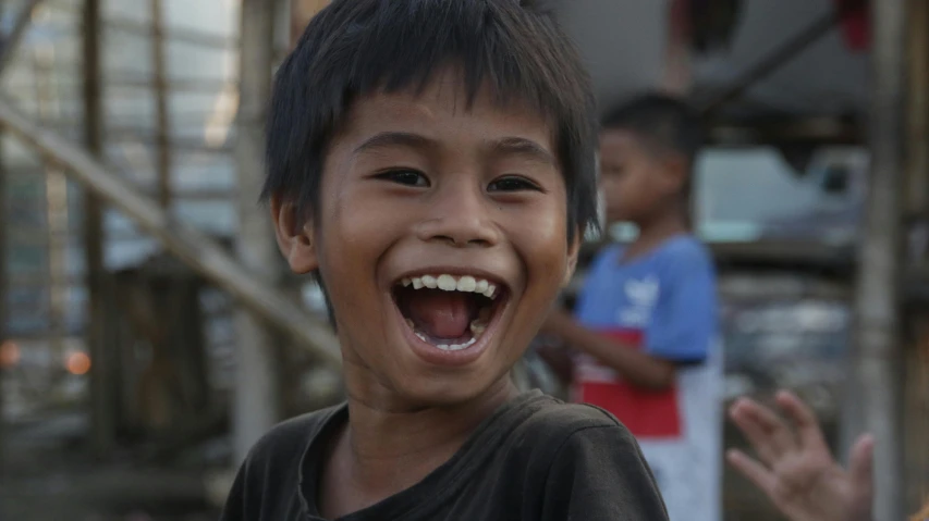 an asian child with dark hair with his mouth open and his hands out