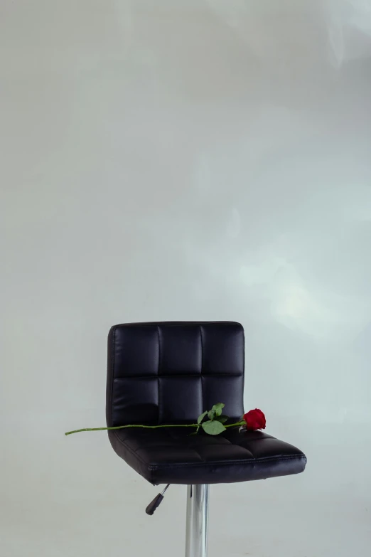 a single red rose on a stool with a grey background