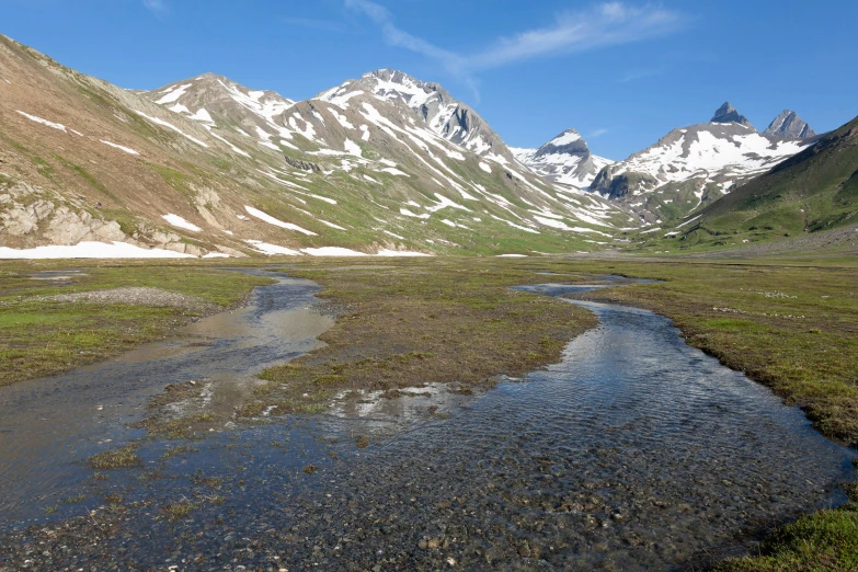 a river meanders through an empty grass covered field