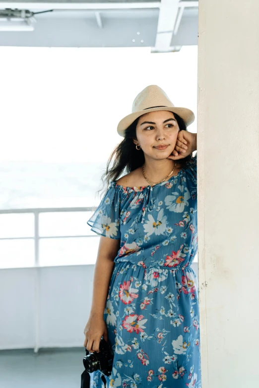 woman with hat leaning against the wall