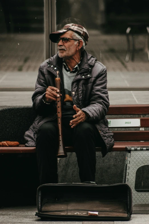 an old man sits on a bench with a musical instrument