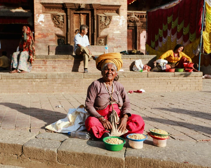 a man sitting down on the side walk next to his food