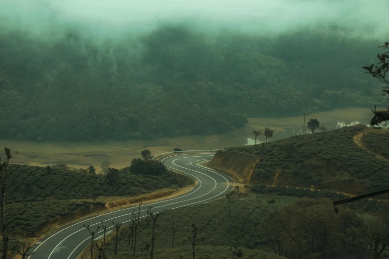 a wide curvey road with green hills on both sides