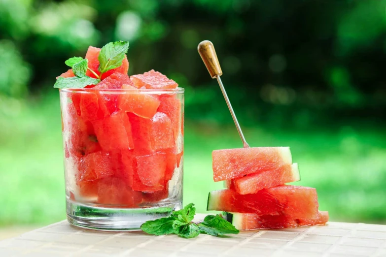 a large glass filled with a drink and watermelon slices