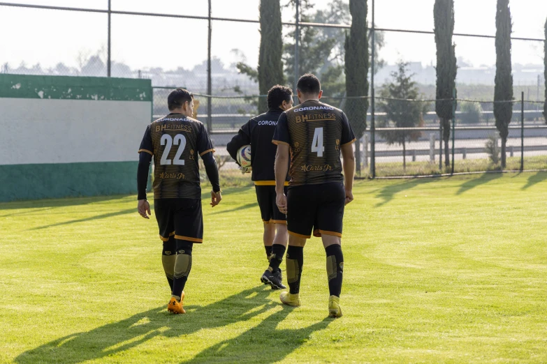 two men are walking across the field with soccer shoes