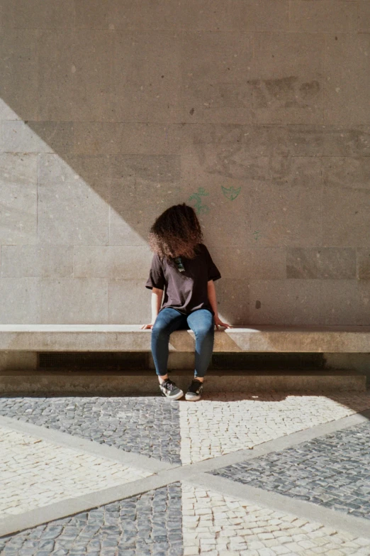 a person sitting on a bench near a wall