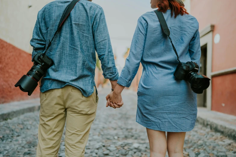 a man and woman hold hands as they walk down a street