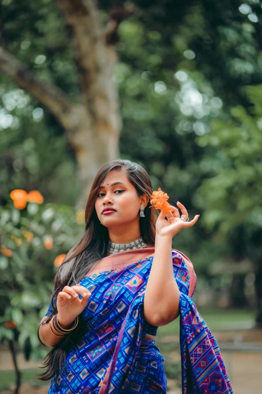 a pretty young indian girl holding a flower in her hand