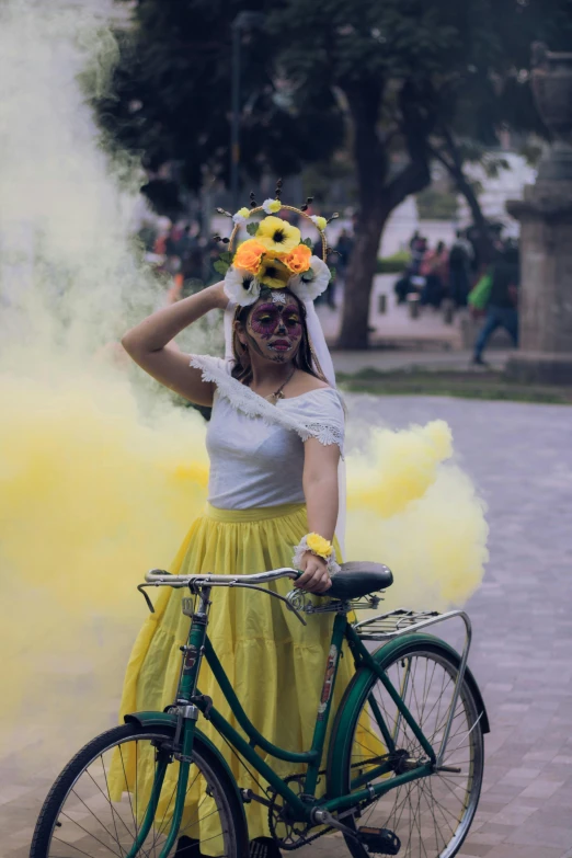 a woman wearing yellow and holding her bike with smoke pouring from it