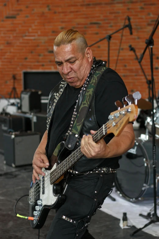 an older man wearing black plays his guitar