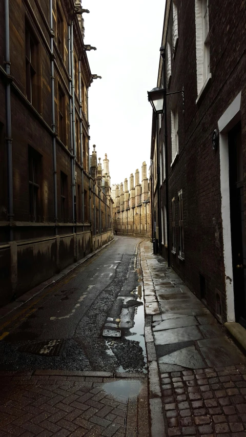 an empty street surrounded by dark brick buildings