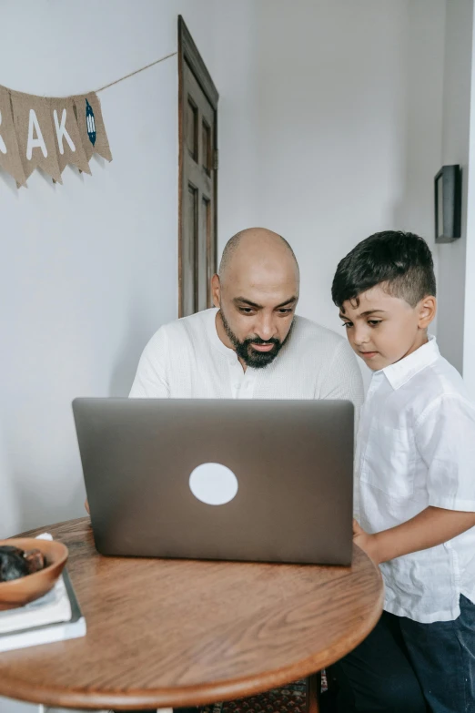 an adult and a child working on a laptop