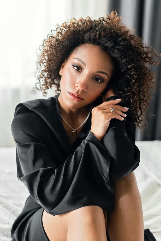 a woman sits on a bed while she has curly hair