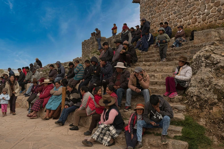 the crowd is watching a large crowd climbing up on a steep mountain