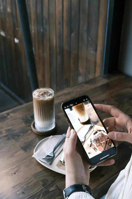 someone is using a cell phone at a wooden table