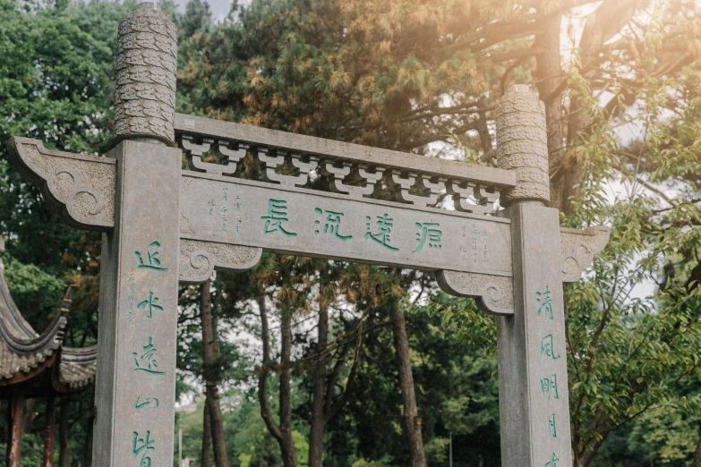 a tall stone sign sitting in front of trees