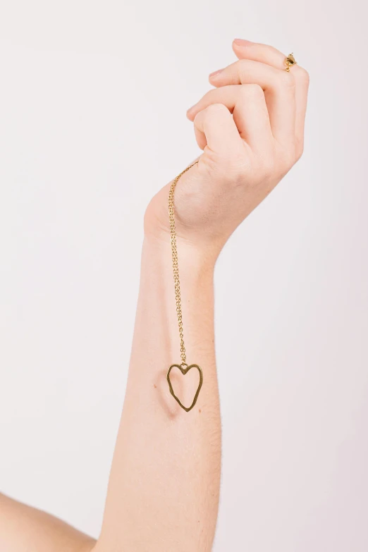 a hand with a heart and a tiny necklace on it