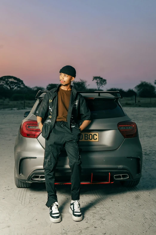 a man leaning on the trunk of a silver car