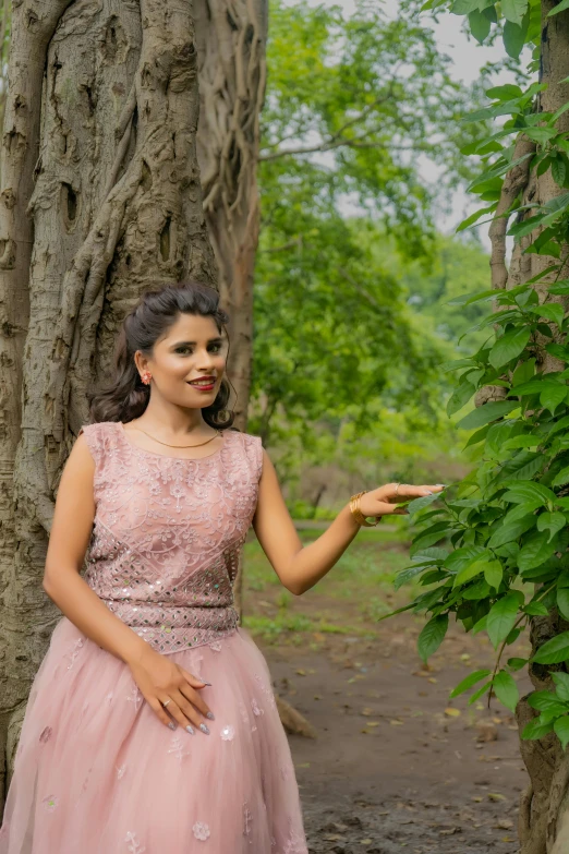 woman wearing pink dress standing next to a tree