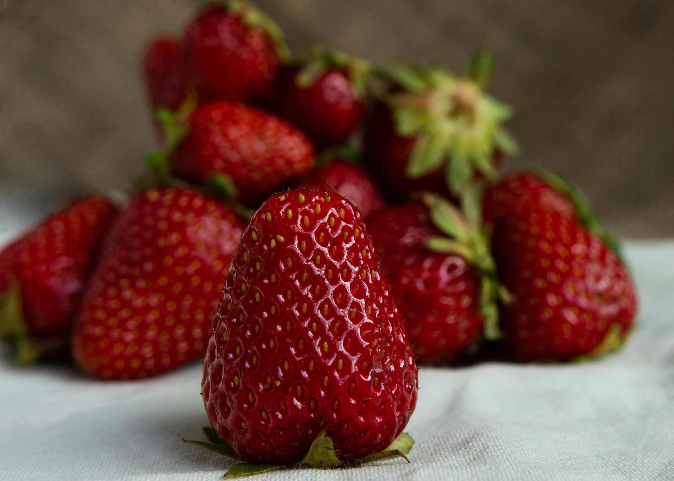 there is a large pile of strawberrys sitting on a linen cloth