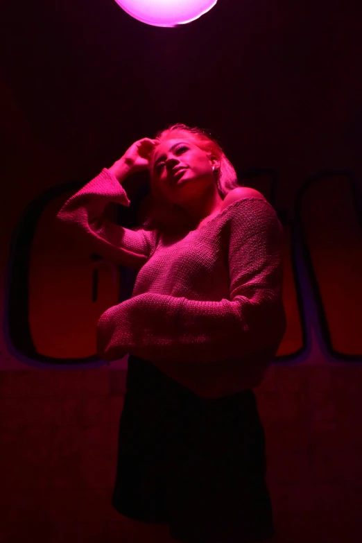 a woman is standing under a red light