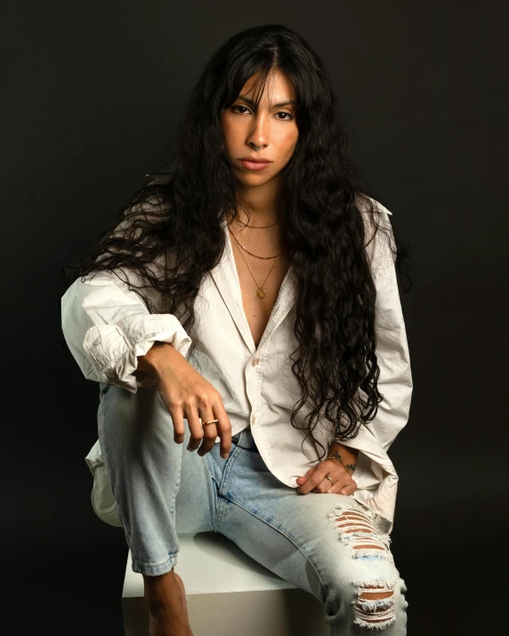 a woman wearing a white blazer sitting on top of a chair