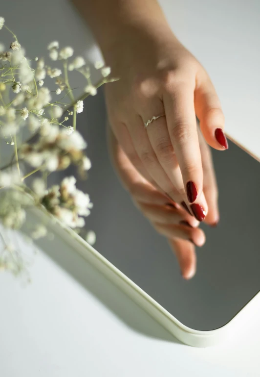 woman touching her nail with her hand in front of the mirror